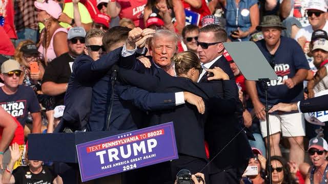 Donald Trump terlihat sempat mengepalkan tangan ke arah hadirin sebelum segera dievakuasi oleh pasukan keamanan.